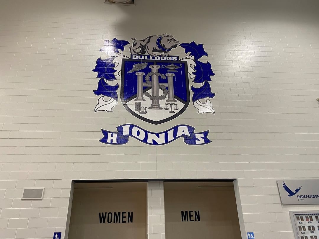A wall with a coat of arms and the words women and men on it.
