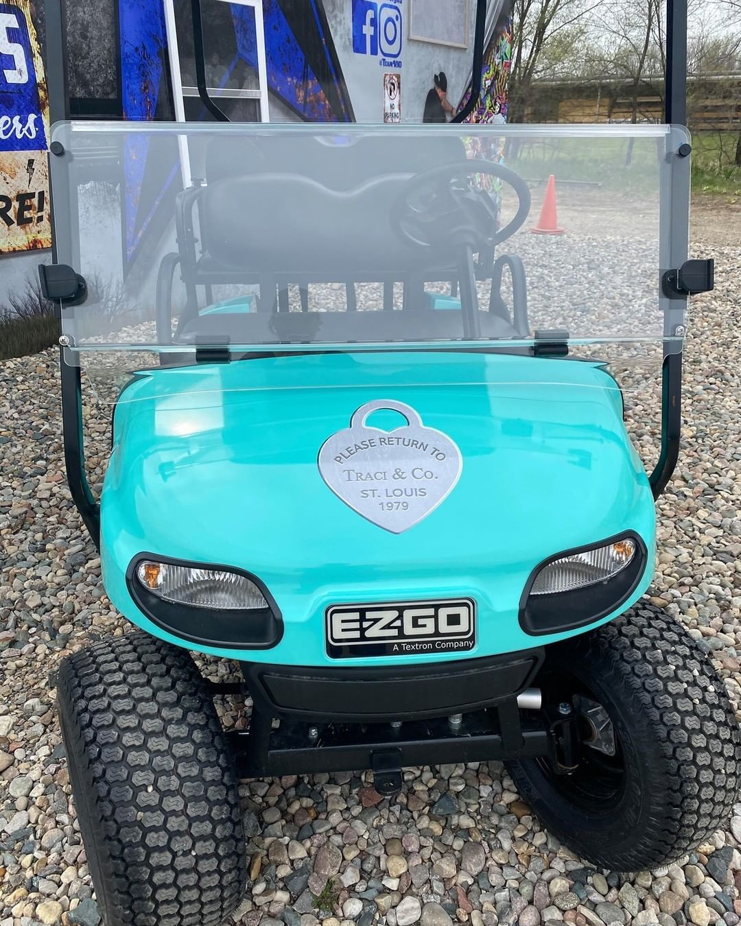 A blue ezgo golf cart is parked on a gravel lot.