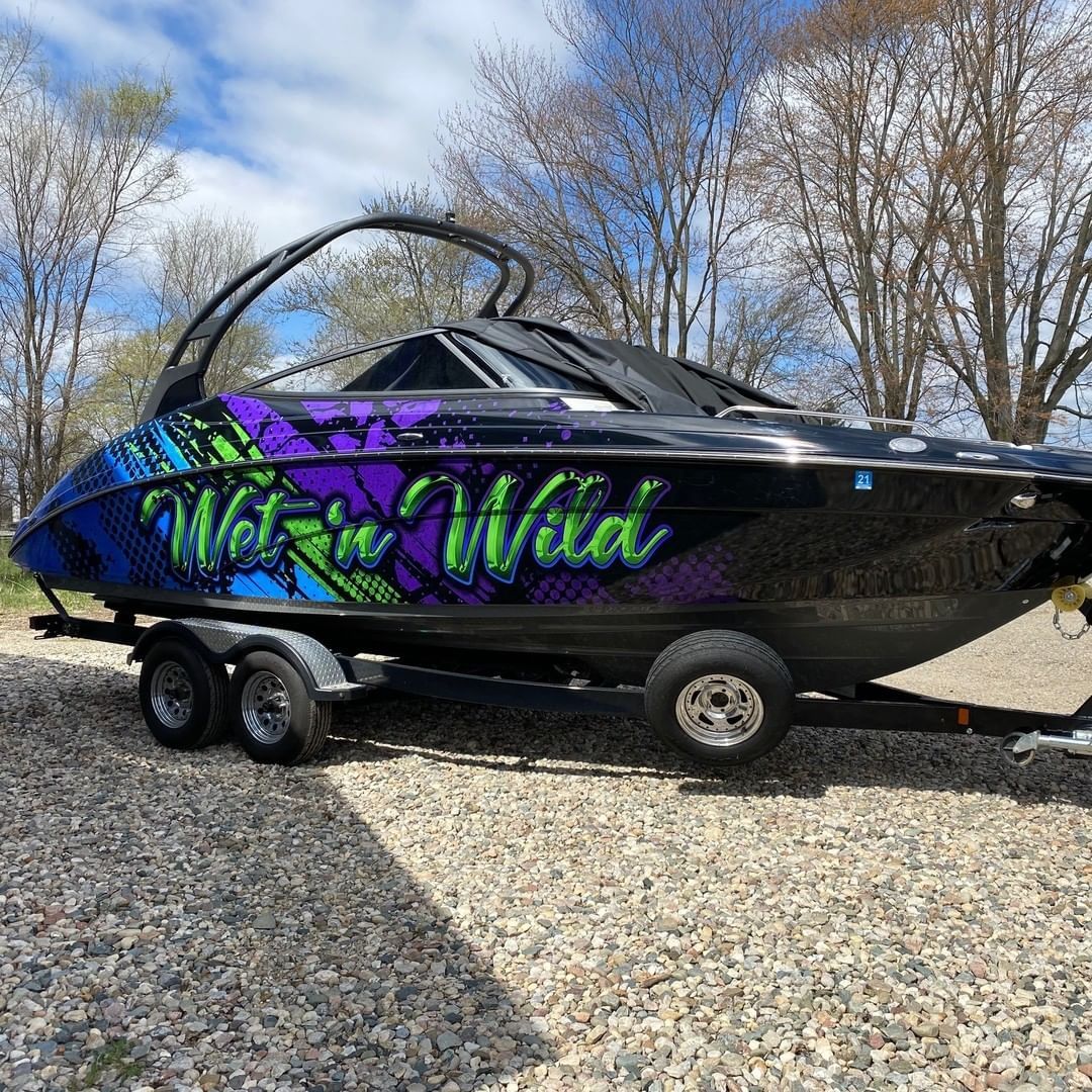 A black and purple boat is parked on a trailer.