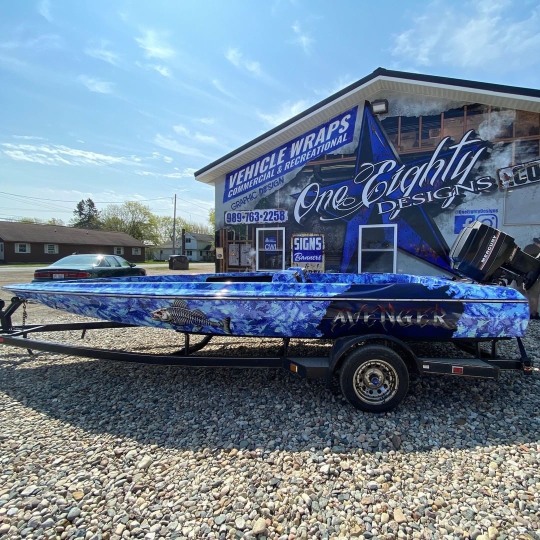 A blue boat is parked on a trailer in front of a building.