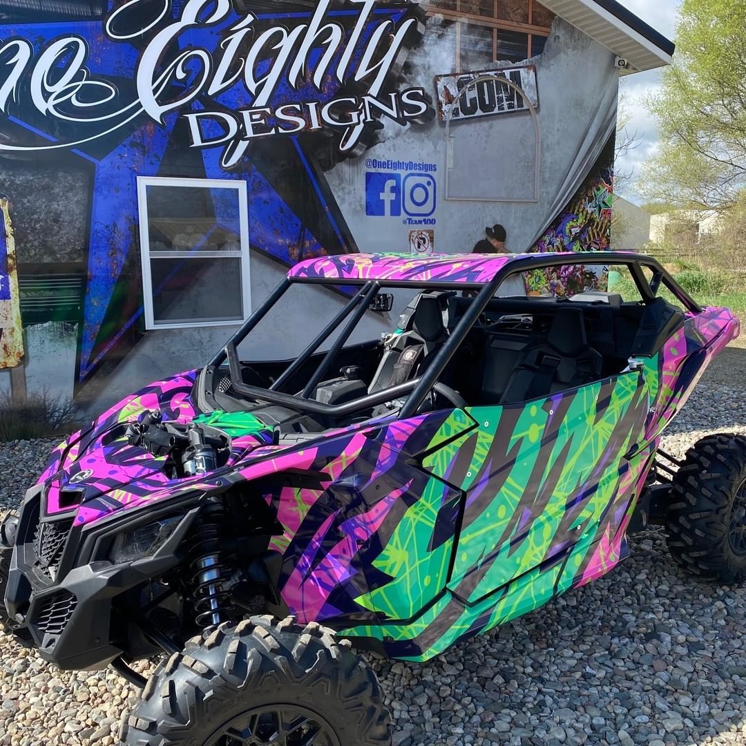 A purple and green atv is parked in front of a building.
