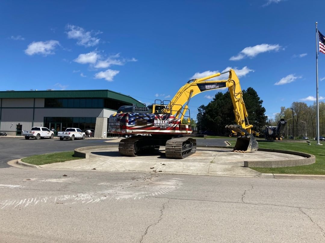 A large yellow excavator is parked in front of a building.