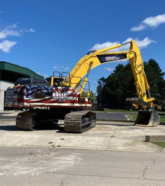 A yellow excavator with an american flag painted on it