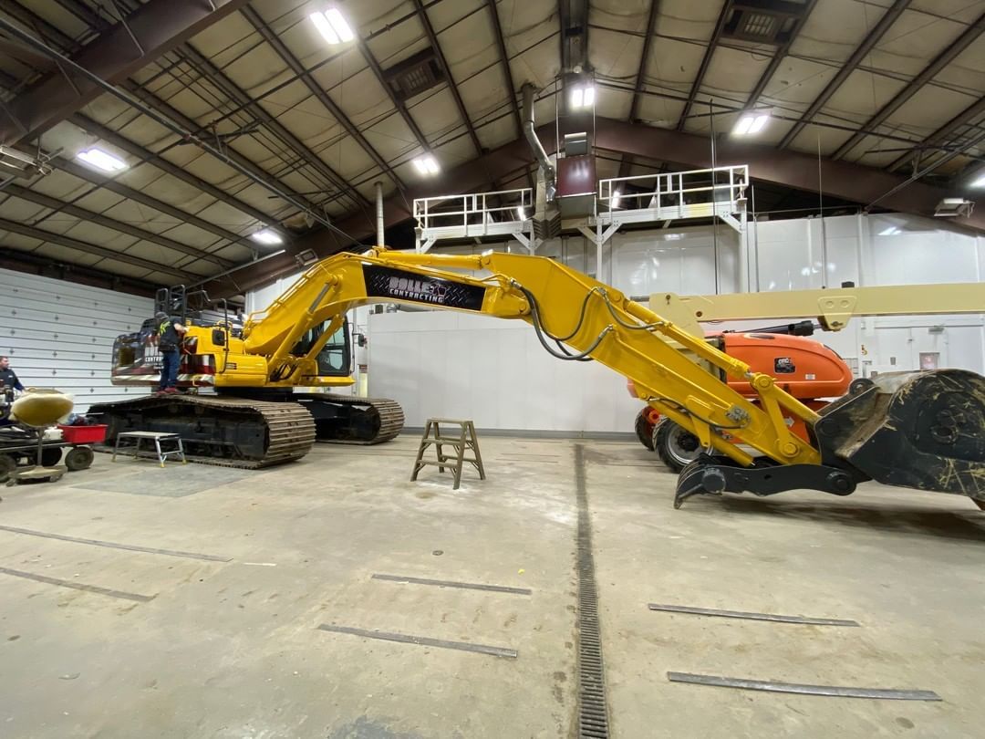 A large yellow excavator is parked in a garage.