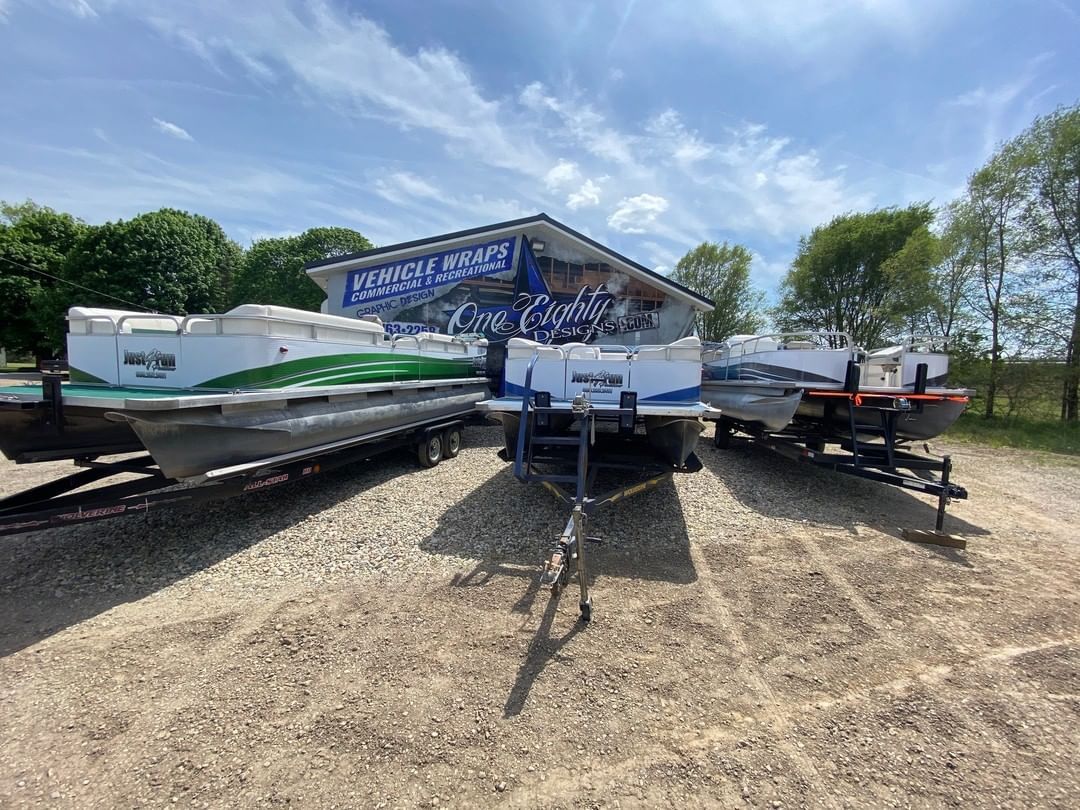 A group of boats are parked in a gravel lot.
