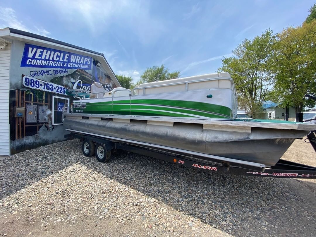A green pontoon boat is parked in front of a building.