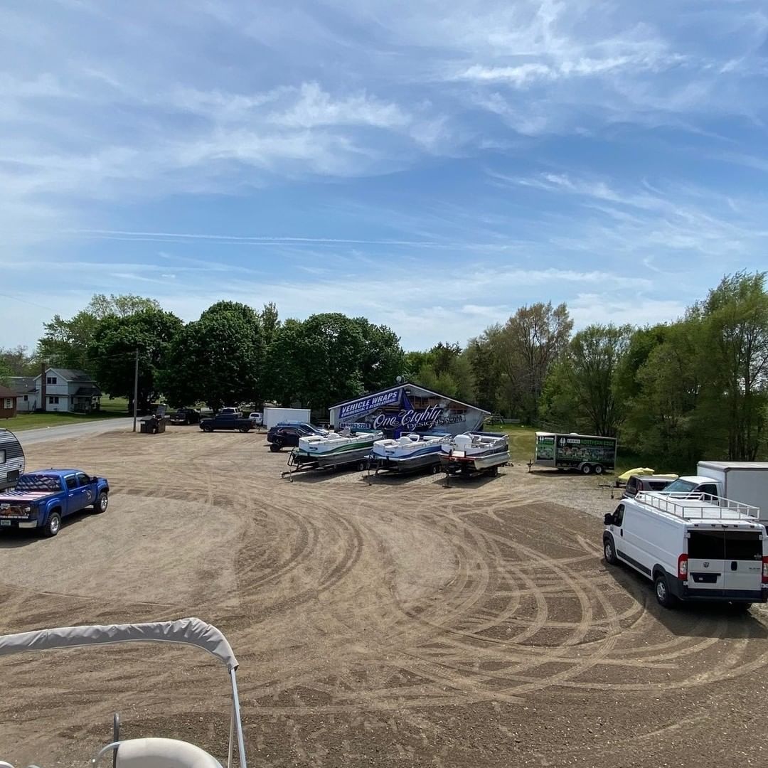 A lot of trucks and trailers are parked in a dirt lot.