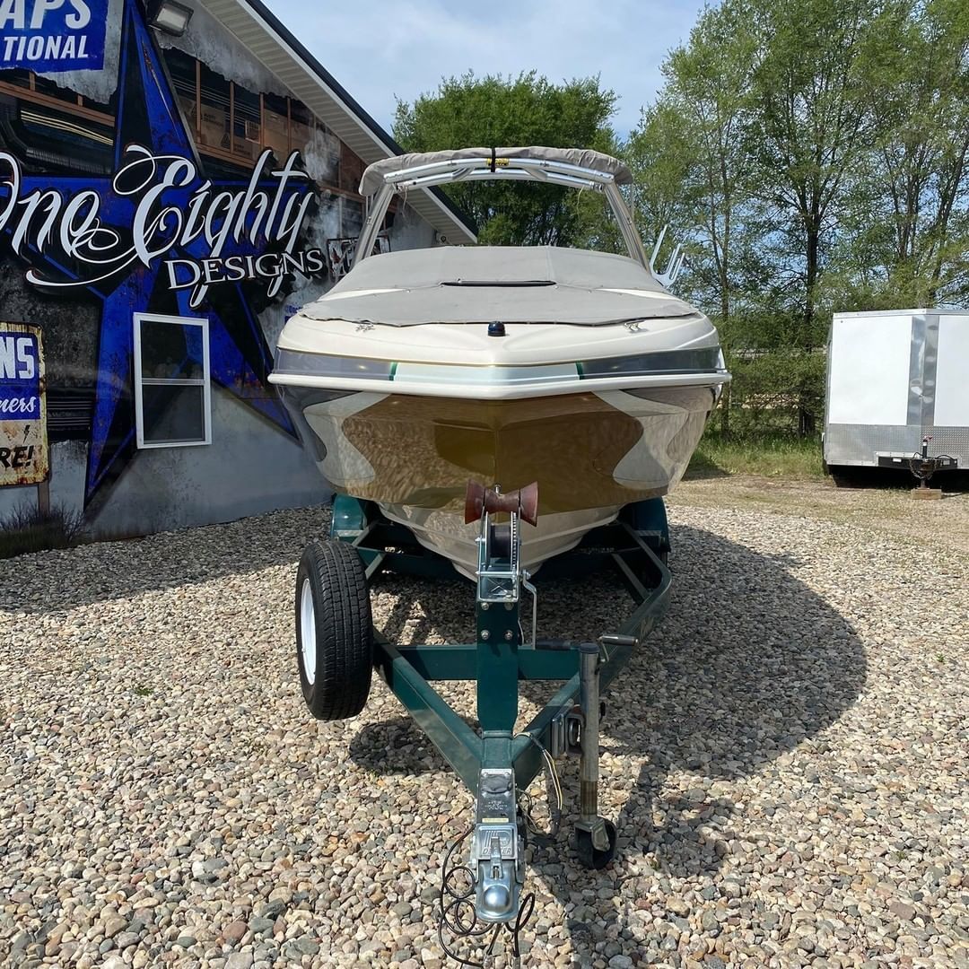 A boat is parked on a trailer in front of a building.