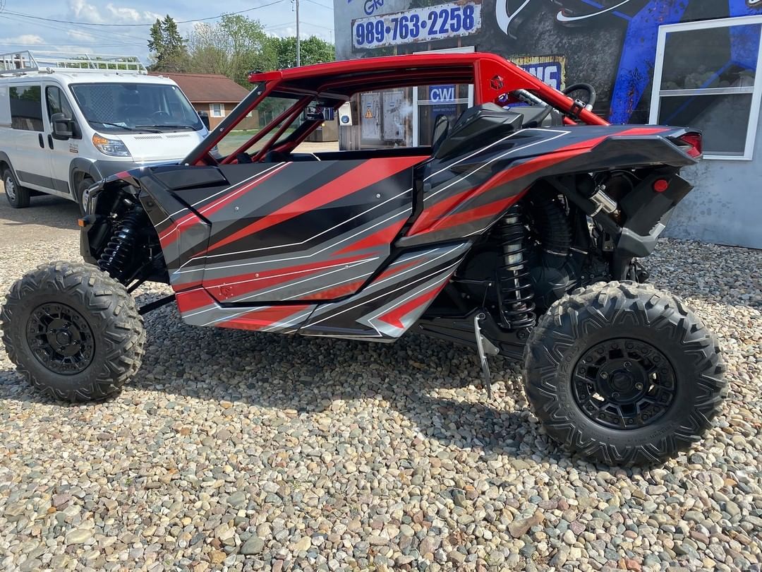 A red and black atv is parked in a gravel lot.