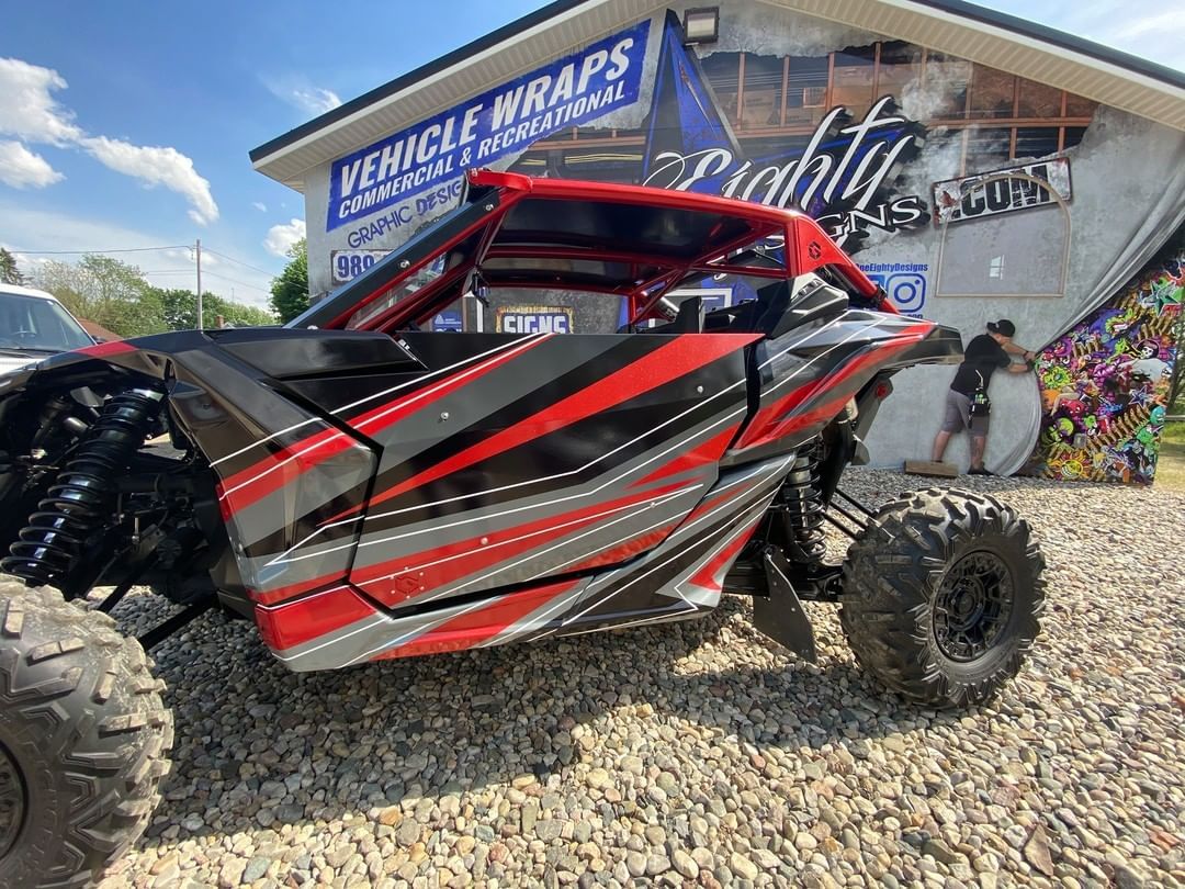 A red and black atv is parked in front of a building.