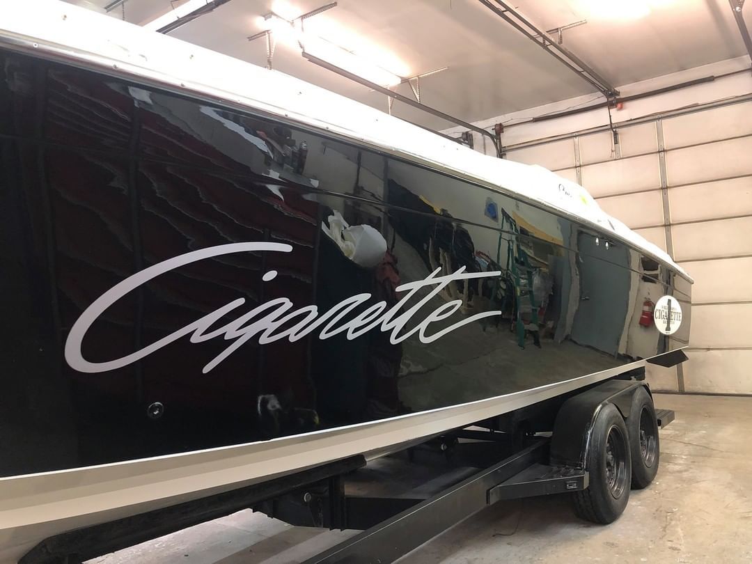 A black boat is parked in a garage next to a garage door.