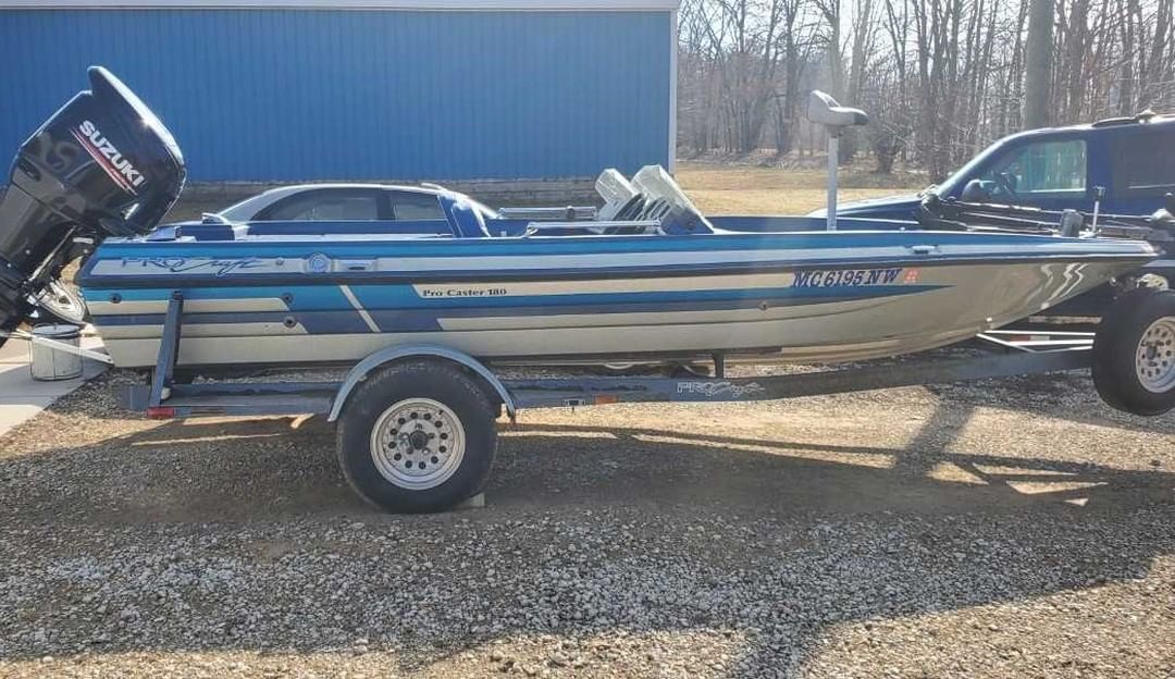 A fishing boat is parked on a trailer next to a truck.