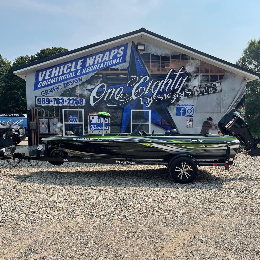A boat is parked in front of a building that says vehicle wraps.