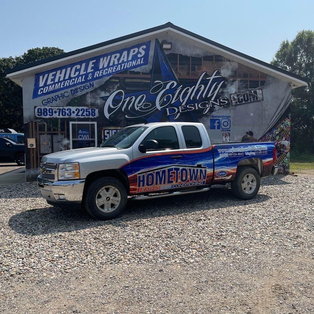 A truck is parked in front of a building that says vehicle wraps.
