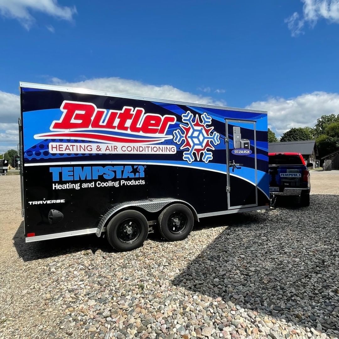 A butler trailer is parked in a gravel lot