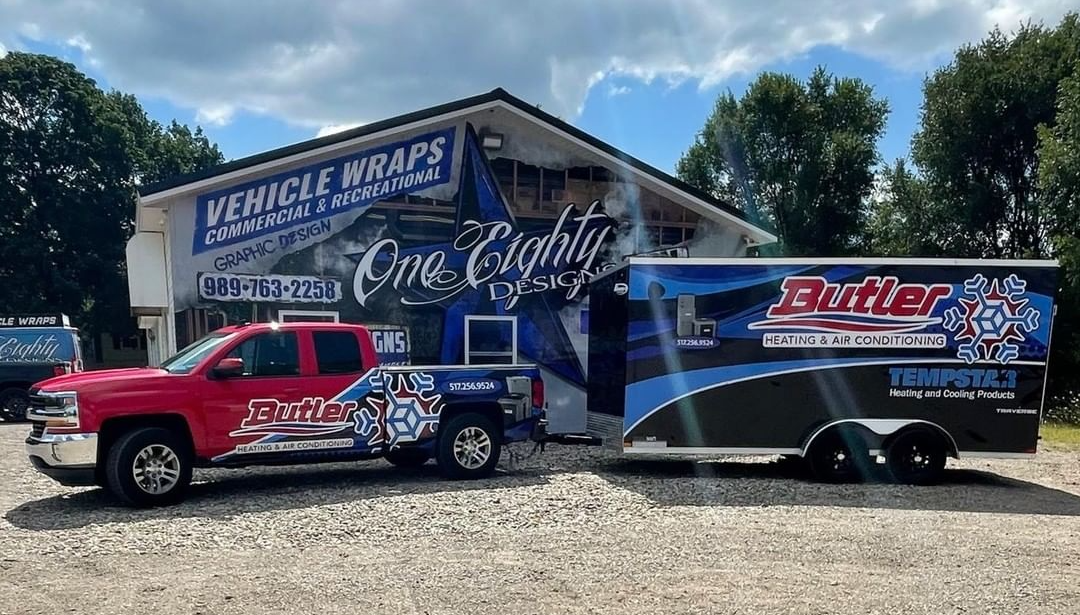 A truck and trailer are parked in front of a building.
