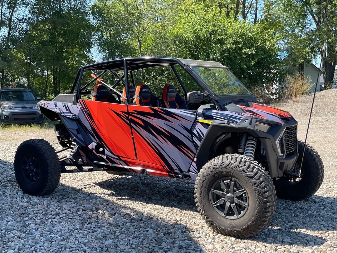 A red and black atv is parked in a gravel lot.