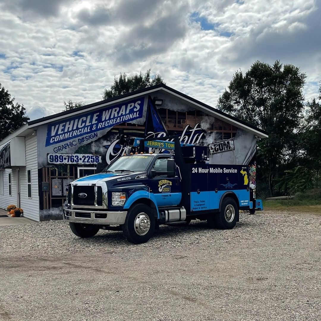 A blue tow truck is parked in front of a building.