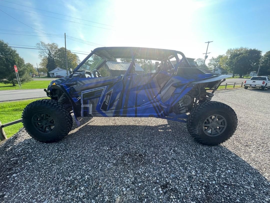 A blue atv is parked on a gravel road.