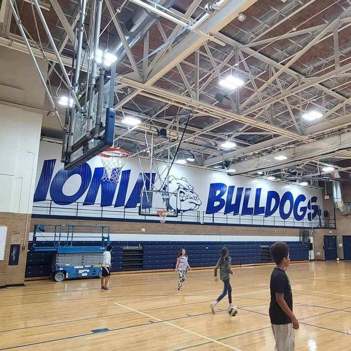 A group of people are playing basketball in a gym.