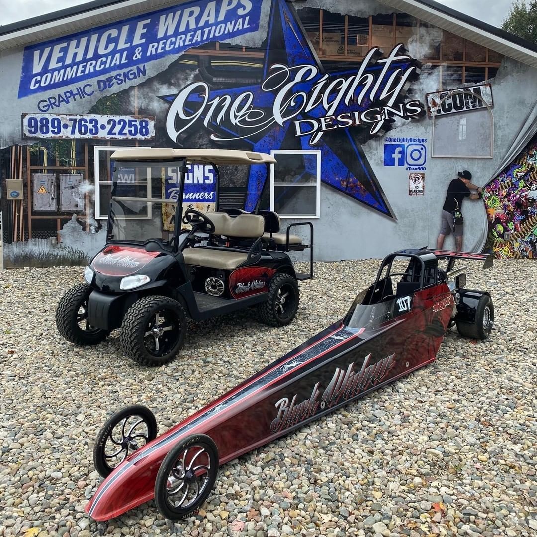 A golf cart and a dragster are parked in front of a building.