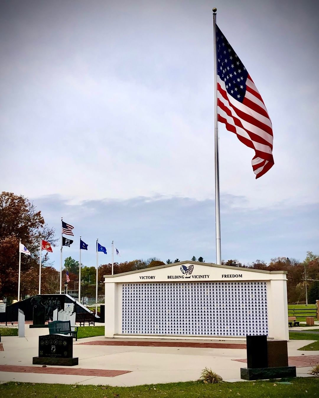A large american flag is flying in front of a memorial