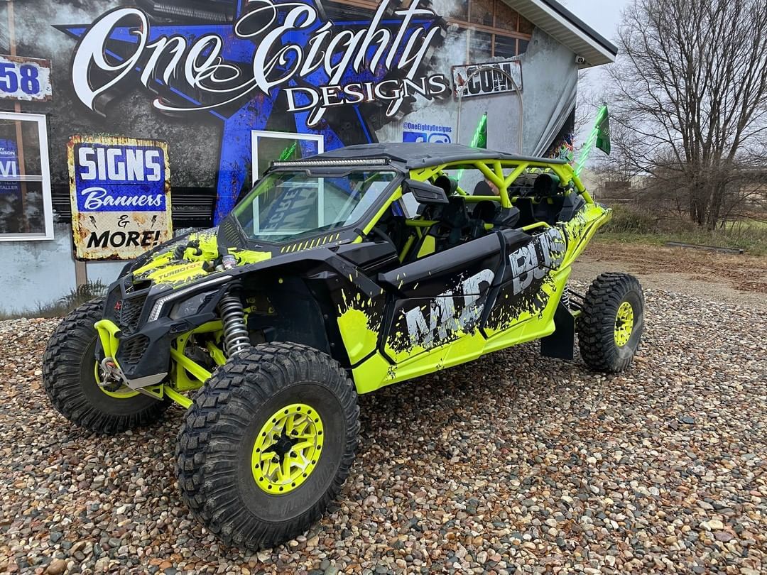 A yellow and black atv is parked in a gravel lot in front of a building.