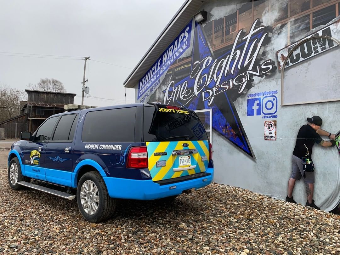 A blue and yellow suv is parked in front of a building.