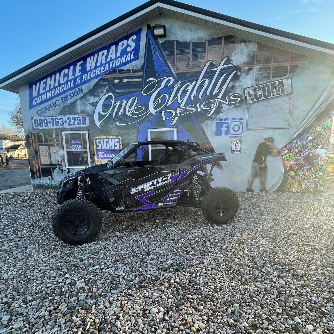 A buggy is parked in front of a building that says vehicle wraps.