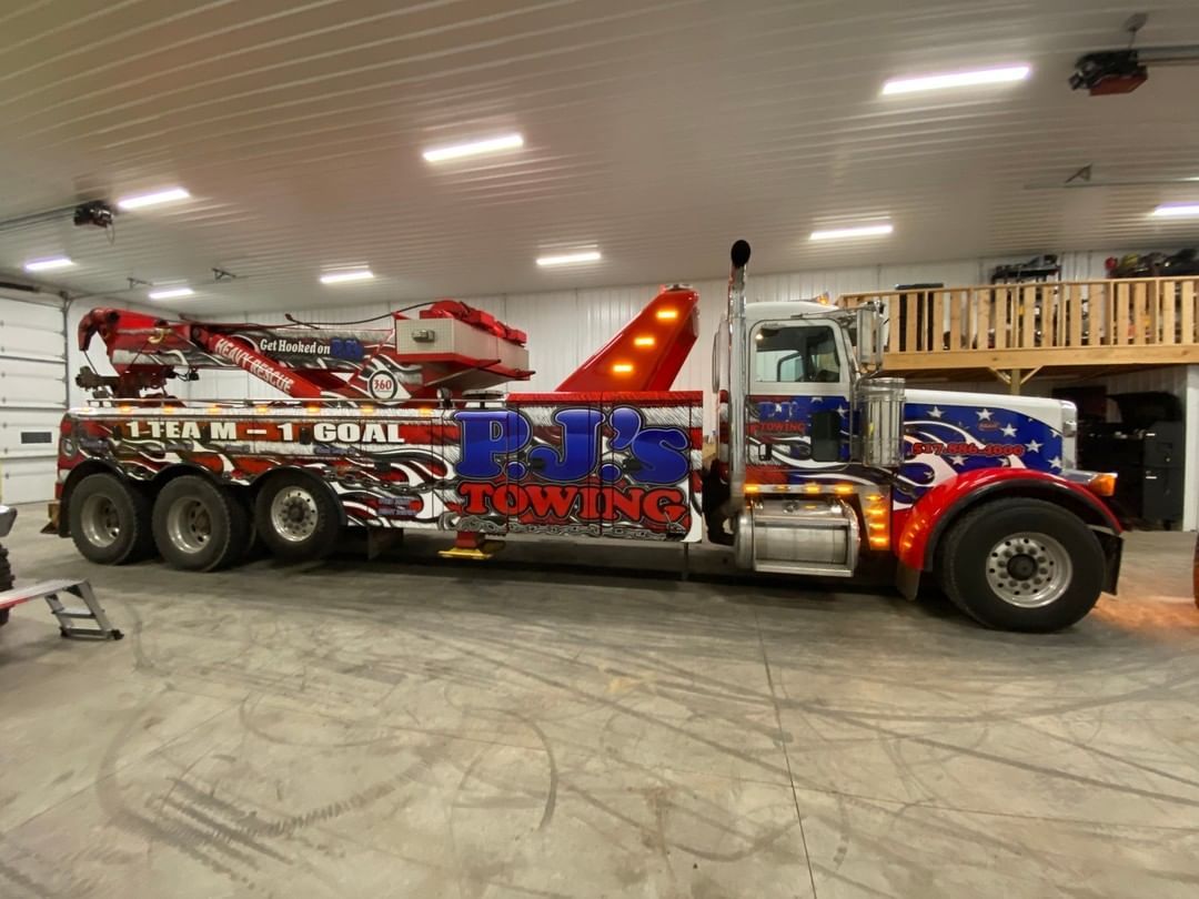 A large tow truck is parked in a garage.