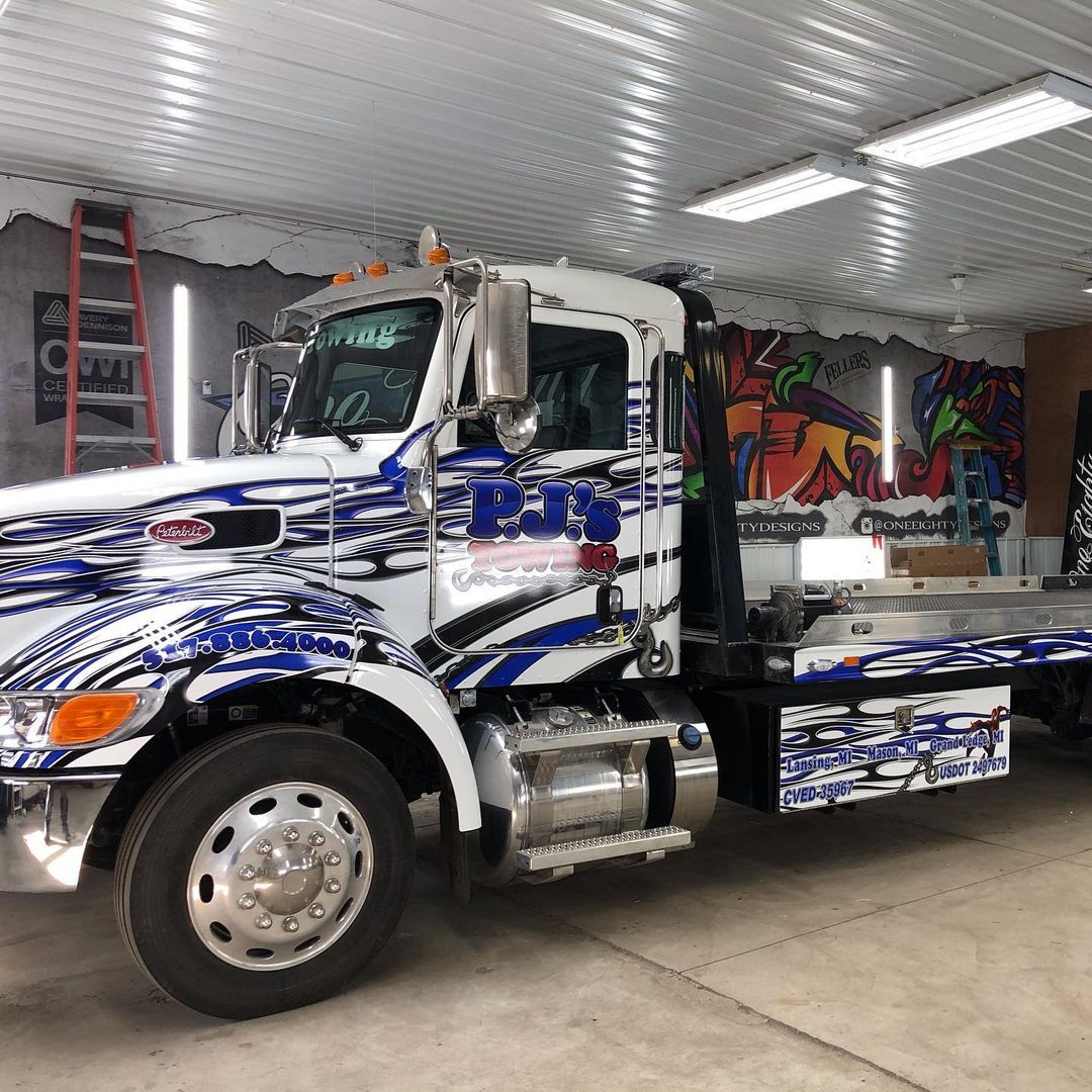 A blue and white tow truck is parked in a garage.