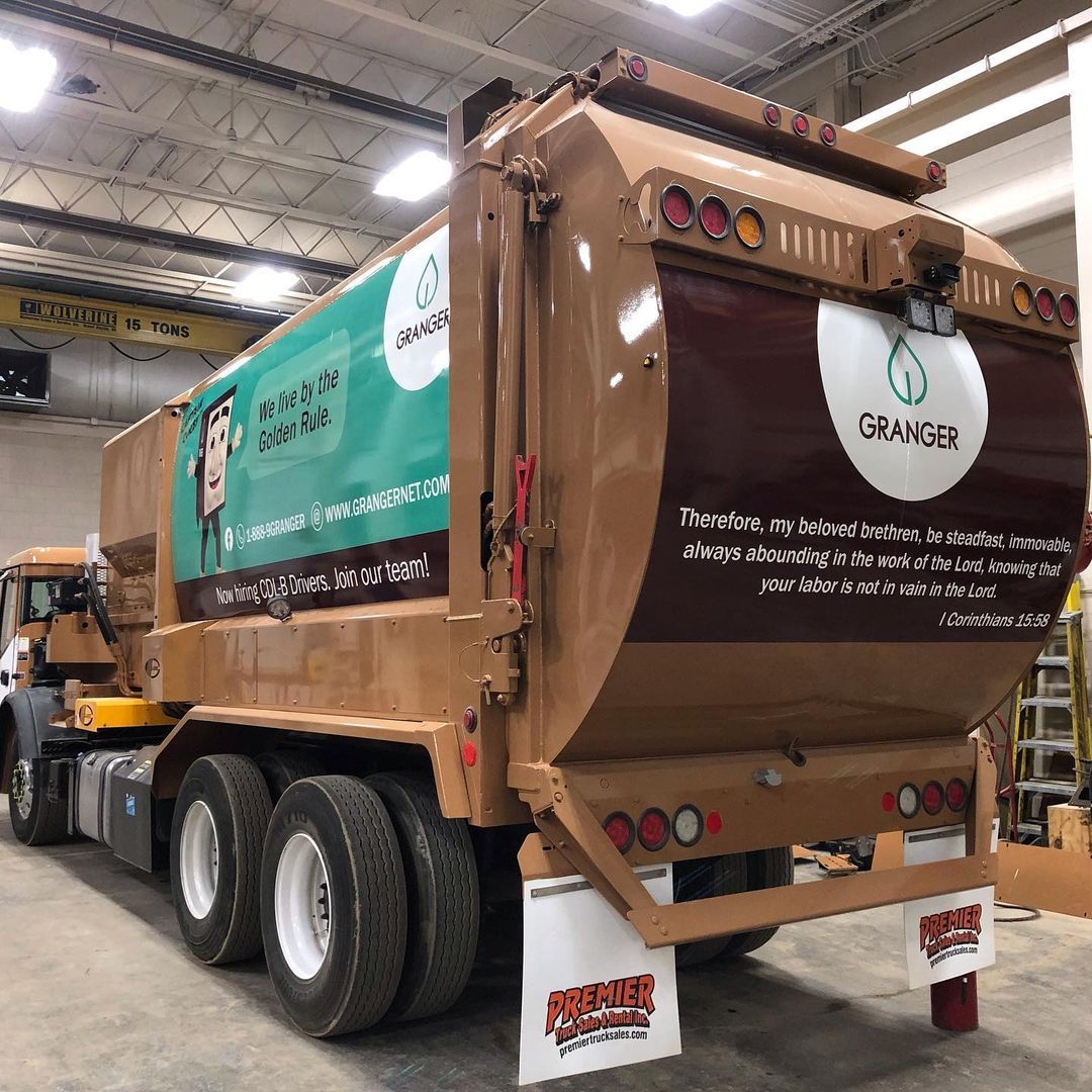 A garbage truck is parked in a garage.