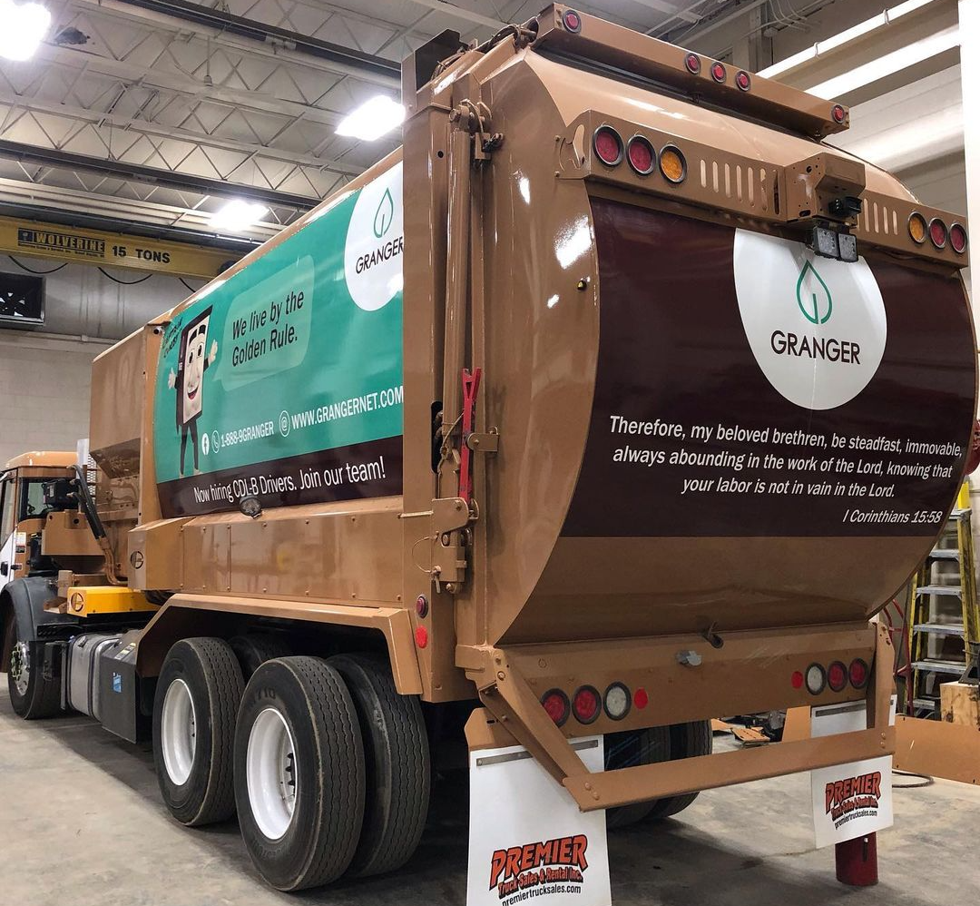 A garbage truck is parked in a garage.