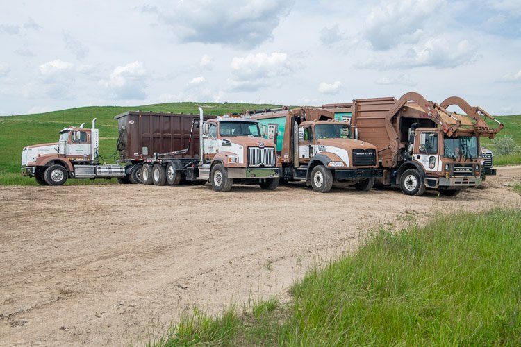 A group of trucks are parked on the side of a dirt road.