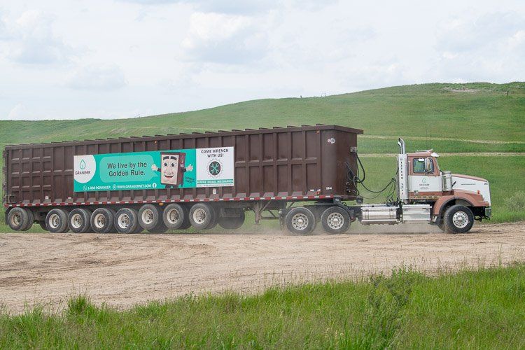 A dump truck is driving down a dirt road.