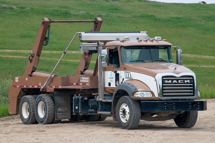A mack dump truck is parked in a dirt field.