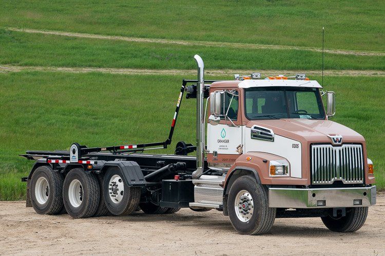 A dump truck is parked in a dirt field.