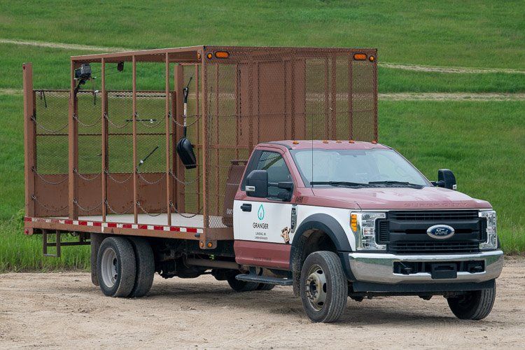 A ford truck with a trailer attached to it is parked in a dirt field.