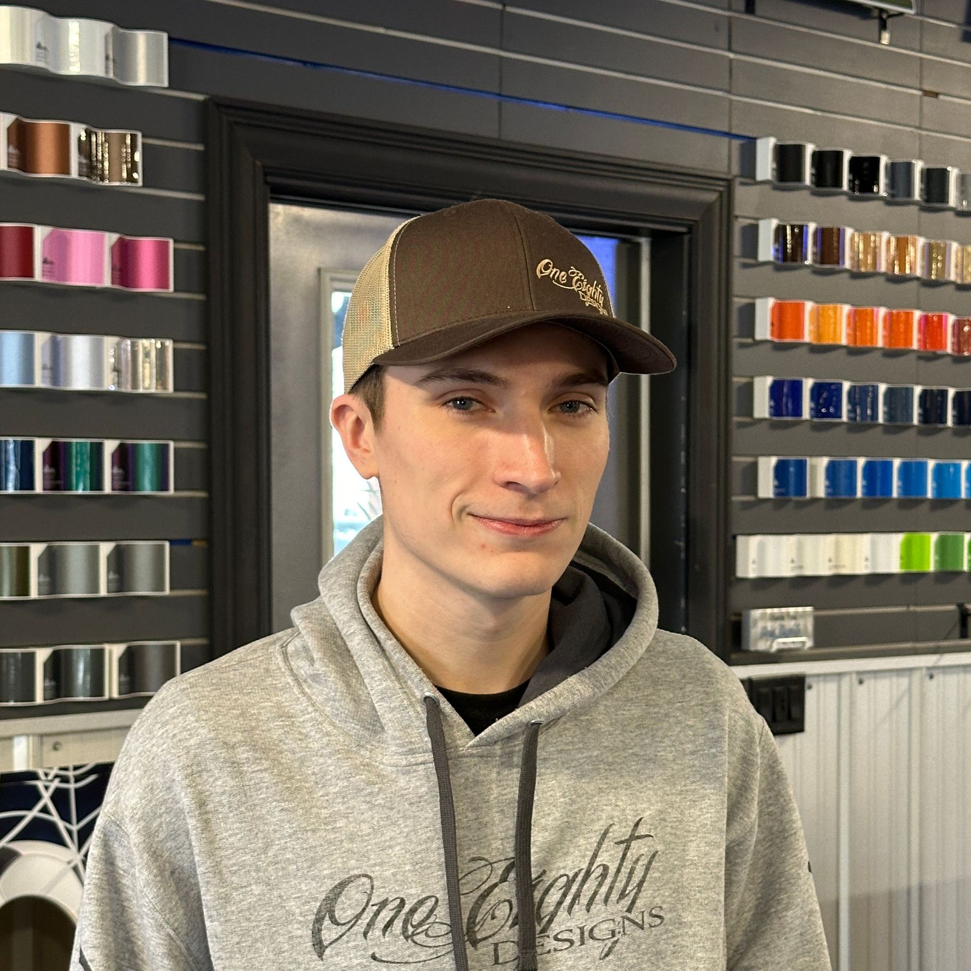 A man wearing a hat and a hoodie with the word one eighty on it