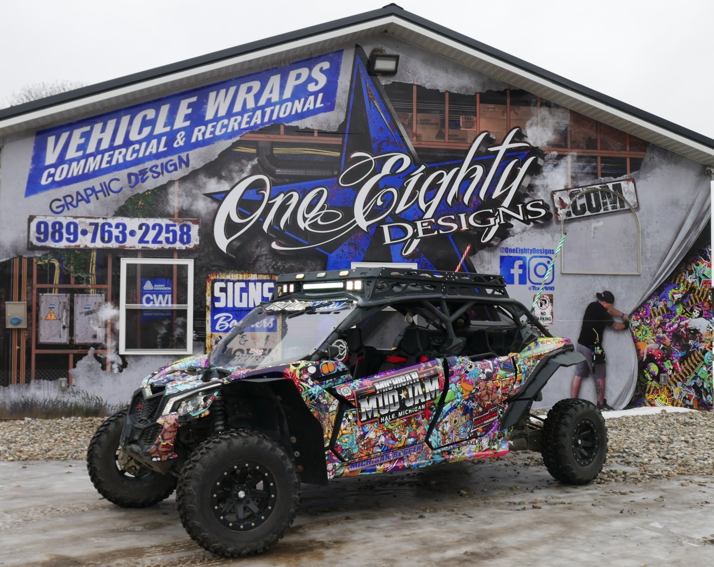 A vehicle wrapped in stickers is parked in front of a building.