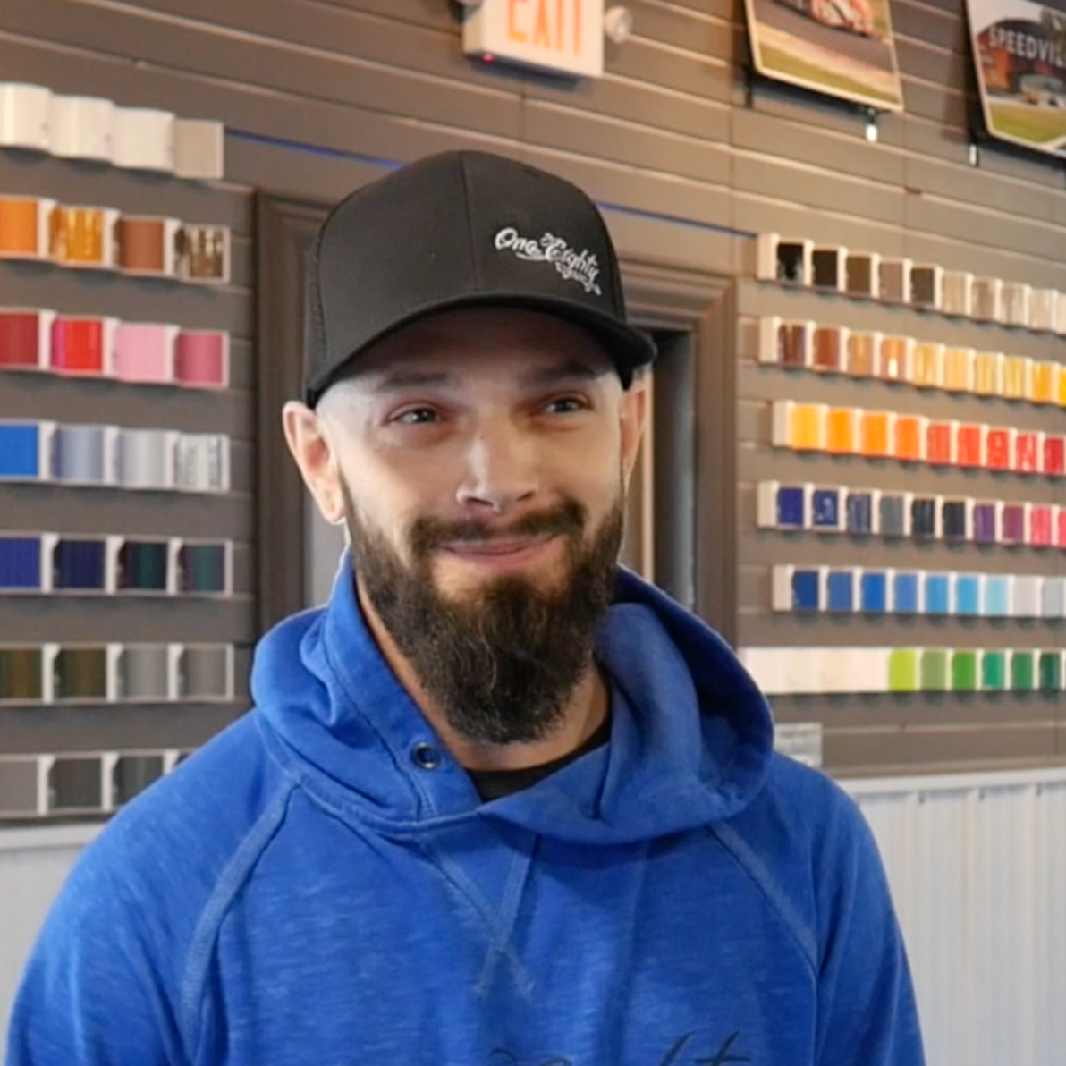 A man with a beard wearing a blue hoodie and a black hat