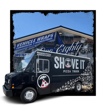 A black pizza truck is parked in front of a building.