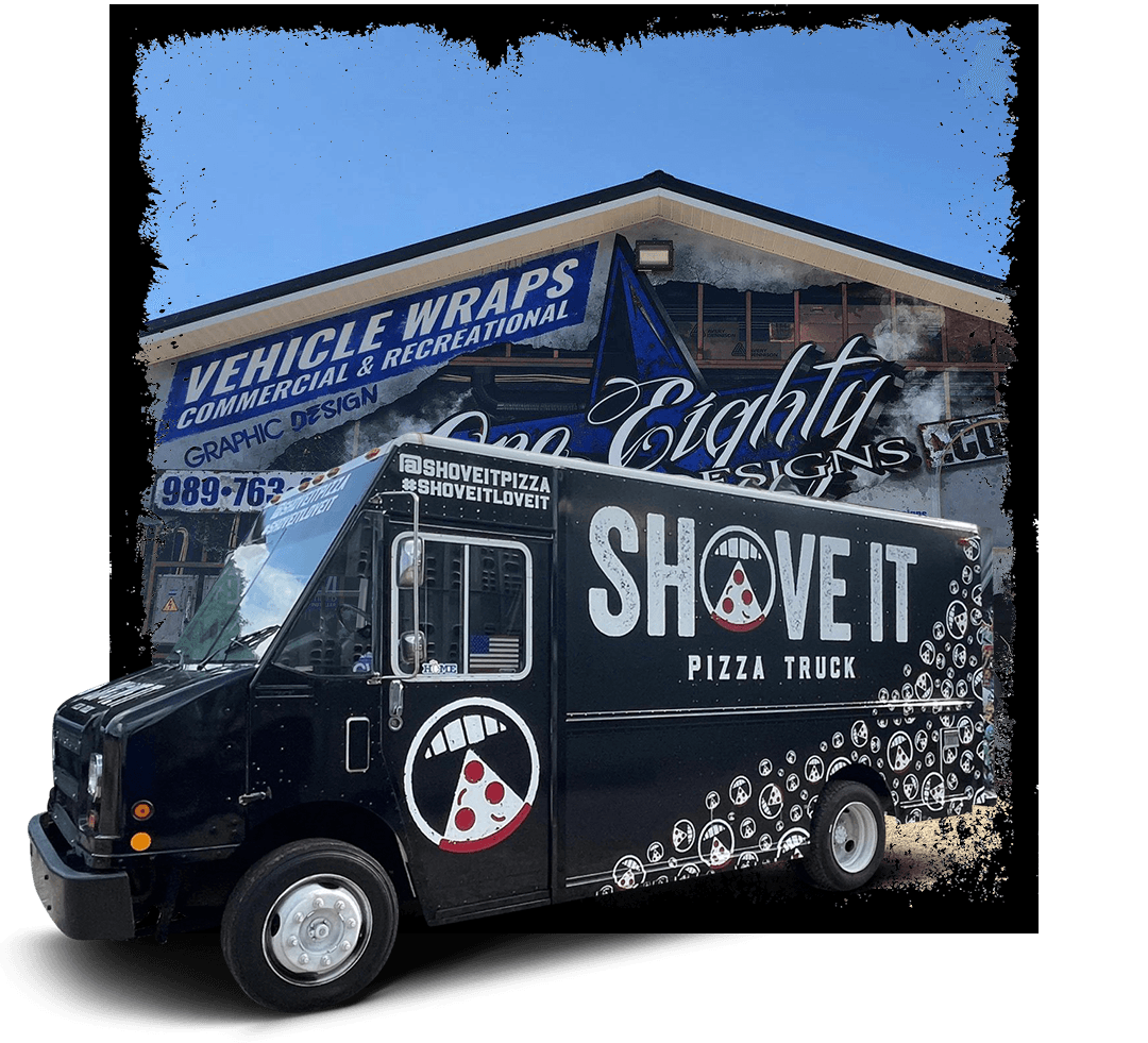 A black pizza truck is parked in front of a building.