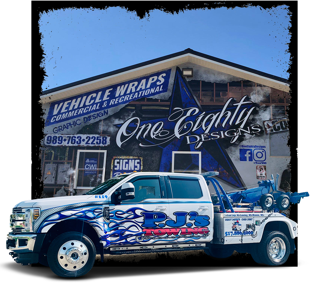 A tow truck is parked in front of a building that says vehicle wraps.