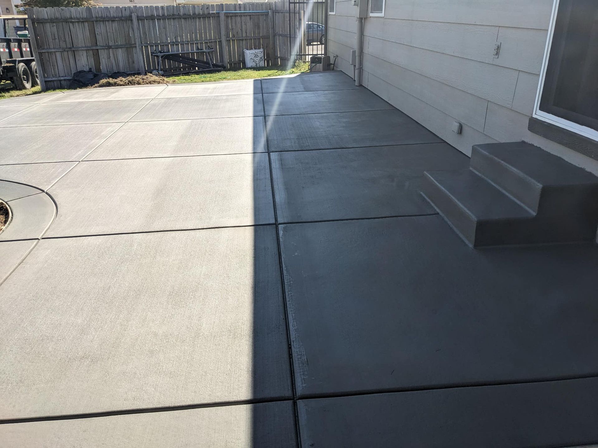 A concrete patio with stairs and a fire pit in front of a house.