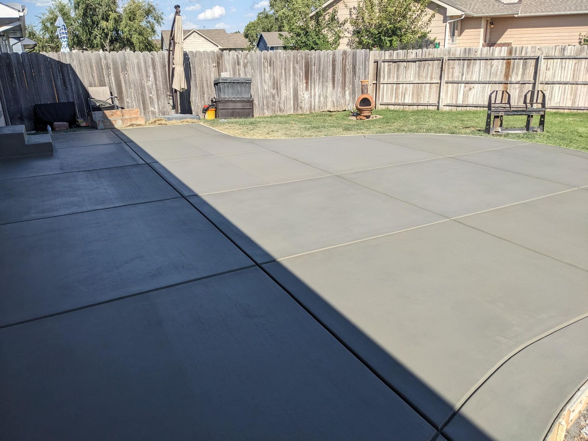 A concrete patio with a wooden fence in the background.
