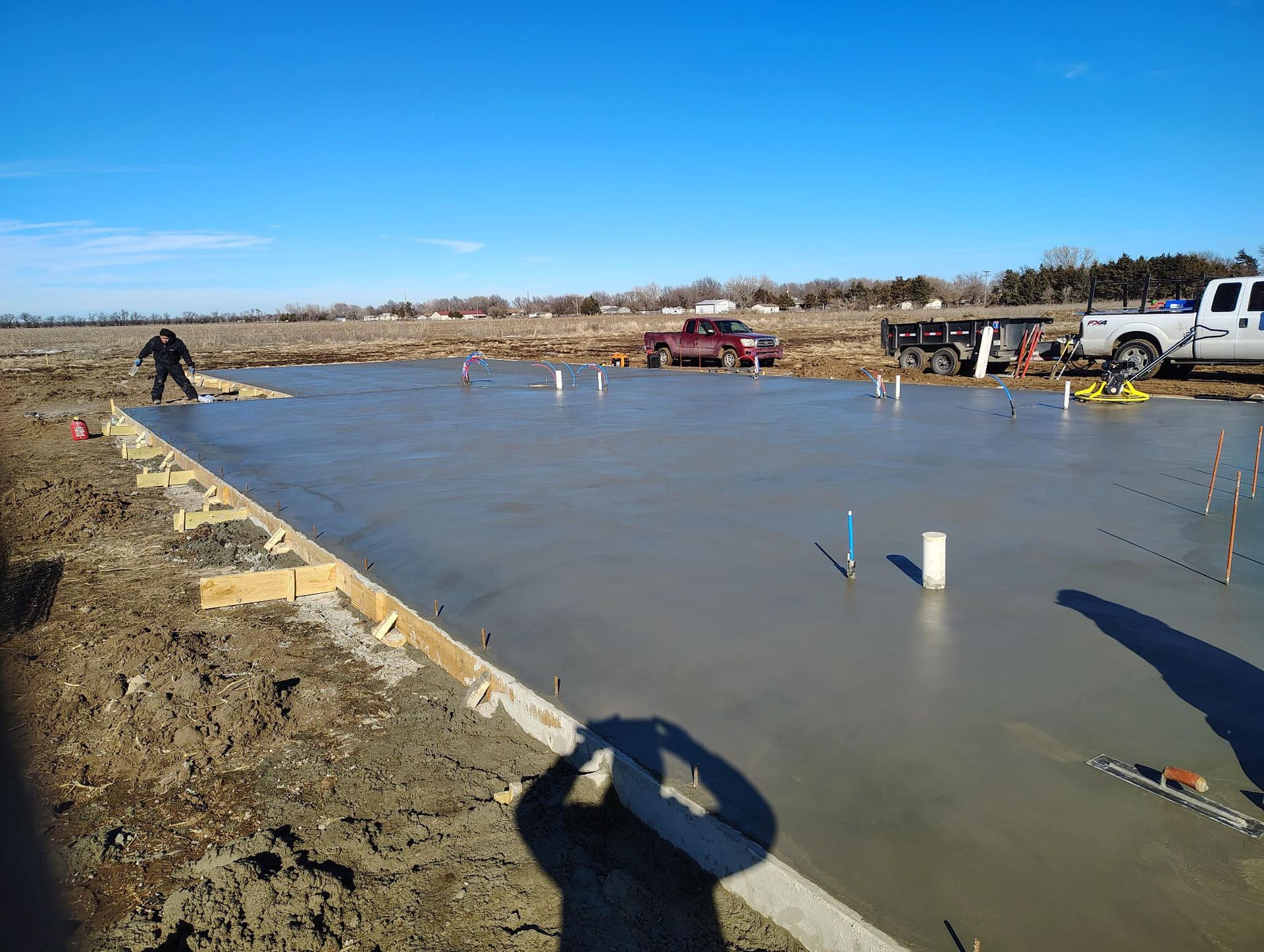 A concrete floor is being built in a field with a truck in the background.
