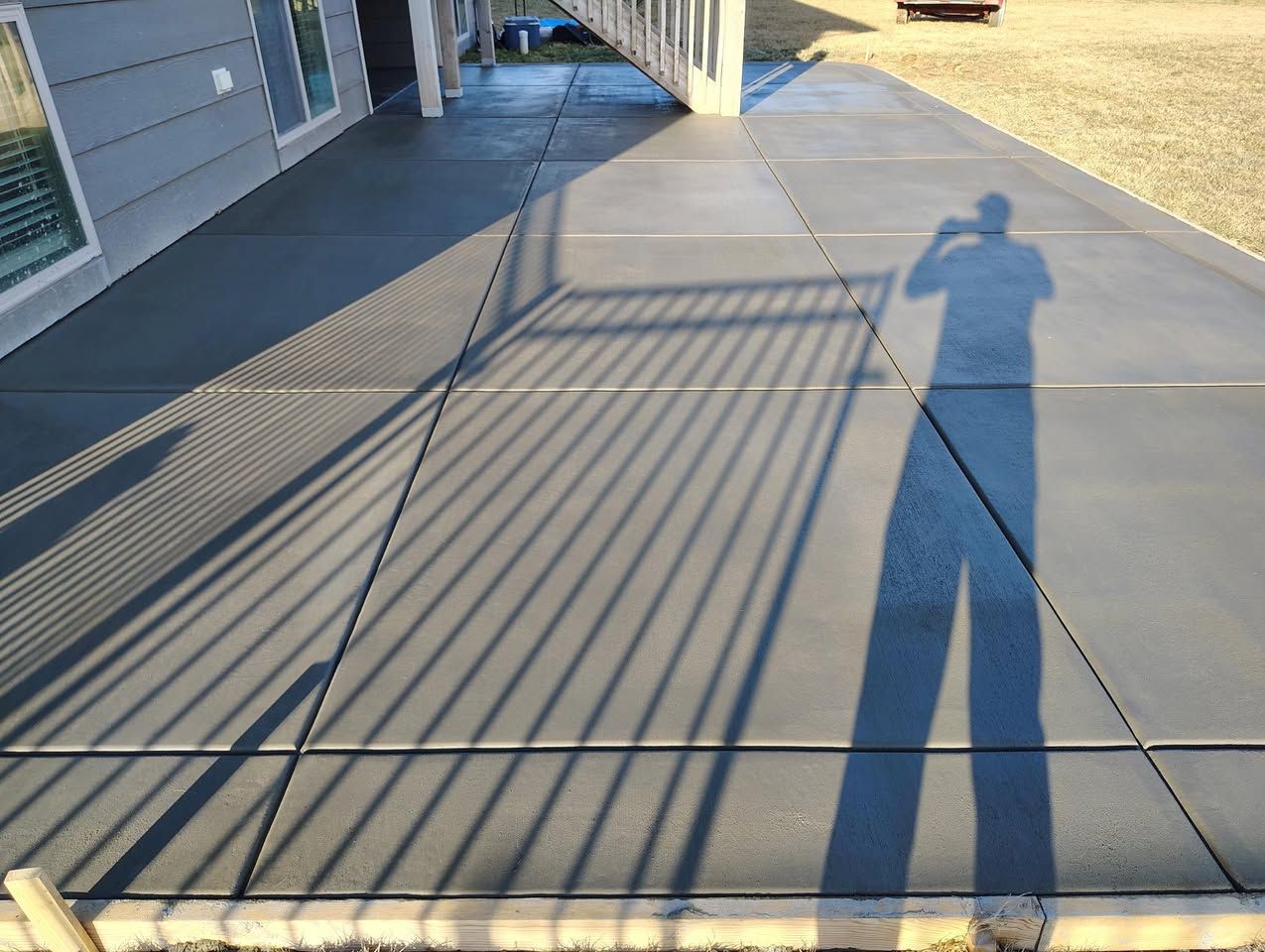 A person is taking a picture of their shadow on a concrete walkway.