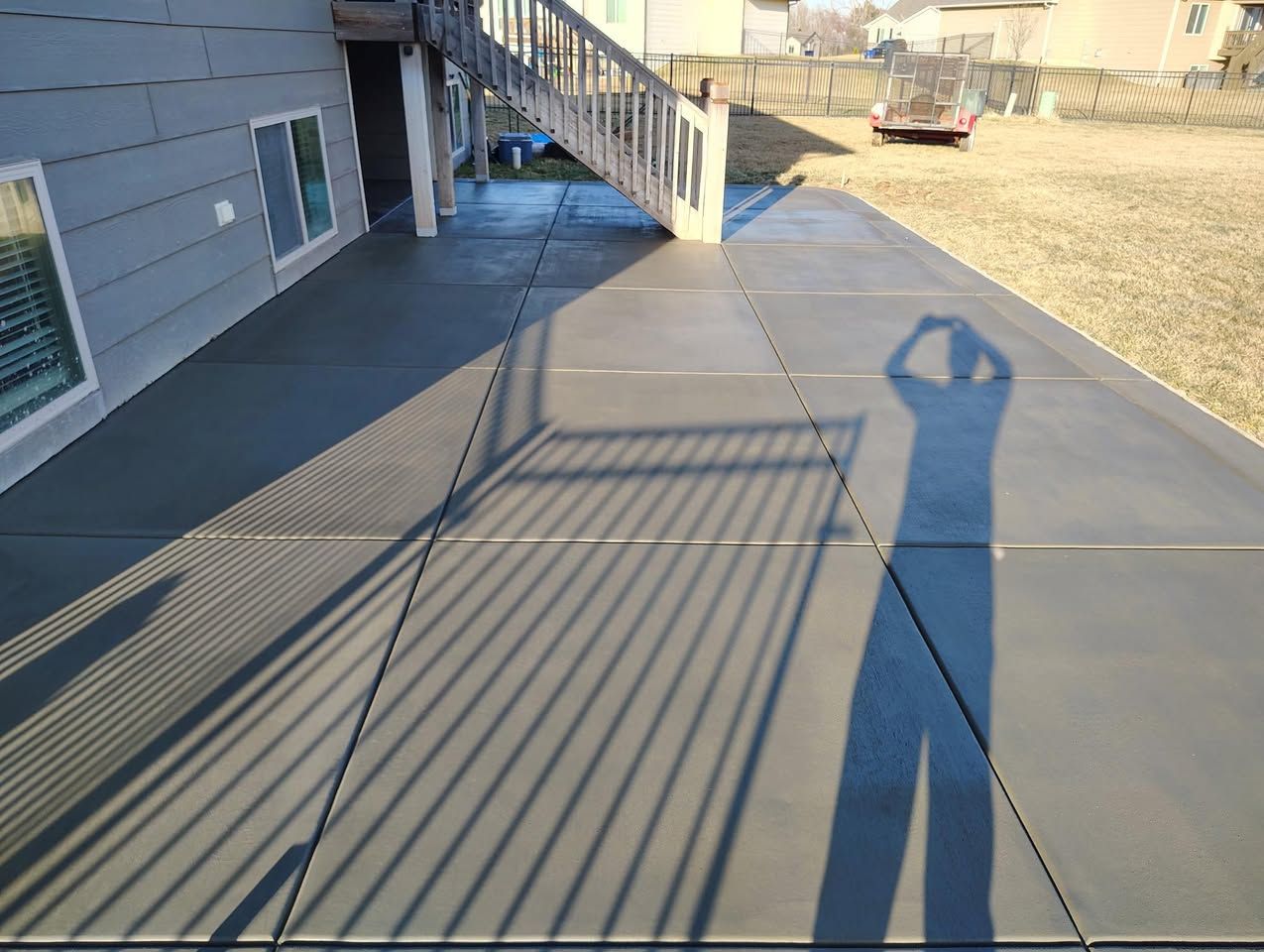 A person is taking a picture of their shadow on a concrete deck.