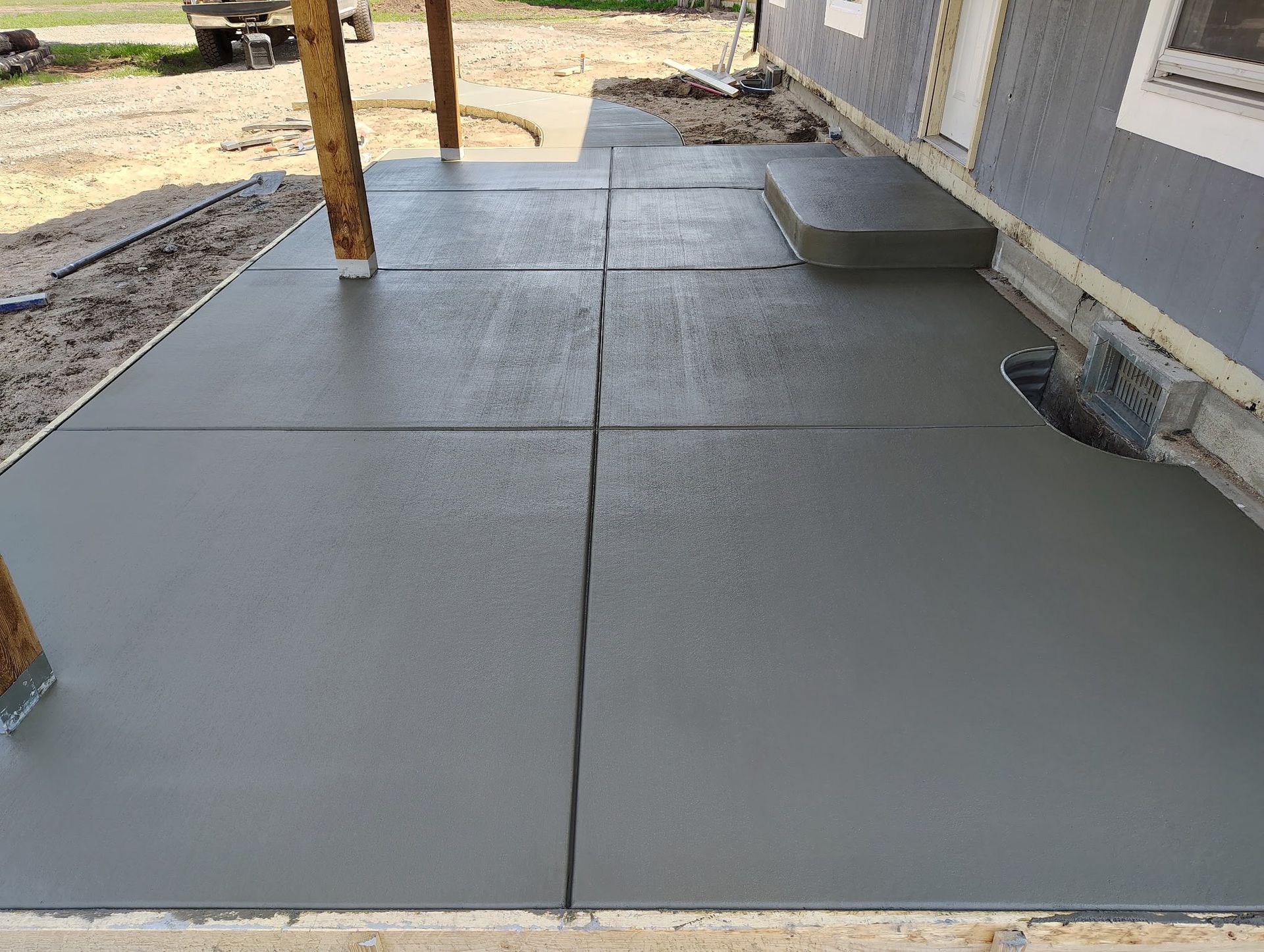 A concrete patio is being built in front of a house.